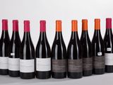 six bottles of red wine lined up in a row on a table