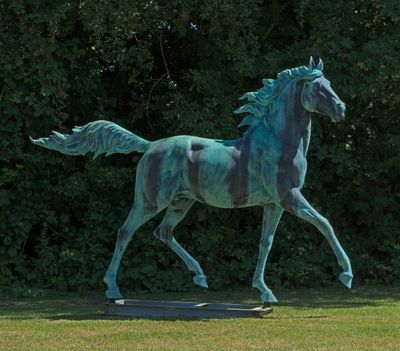 une statue représentant un cheval au galop dans l'herbe