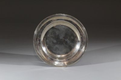 une assiette en argent posée sur une table, sur fond noir