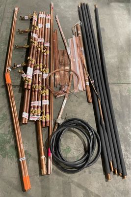 a bunch of copper pipes sitting on top of a floor next to a hose