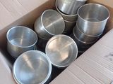 une boîte en carton remplie de casseroles en métal posée par terre