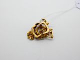 a gold brooch on a white surface with a tag