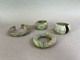 four pieces of ancient bronze bracelets on a table