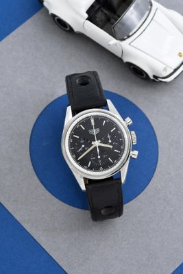 une montre et une petite voiture sur un fond bleu et gris