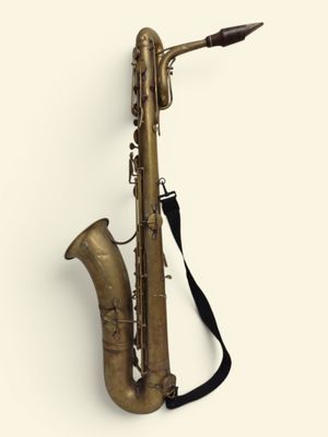 un gros plan d'un saxophone sur fond blanc, muni d'une sangle noire