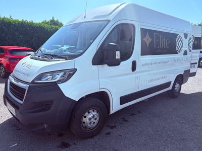 La camionnette blanche est garée sur le parking, avec d'autres voitures en arrière-plan.