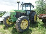 a tractor that is sitting in the grass near a trailer