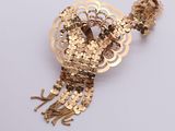 gold sequinned brooch with fringes and beads on a white background