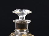 une bouteille en verre ornée d'un motif, posée sur une surface noire