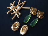 gold and green earrings and brooches on a black surface