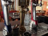 three beer taps on top of a metal counter in a restaurant