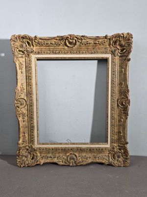 un miroir ancien à cadre doré, orné d'un motif décoratif sur le pourtour