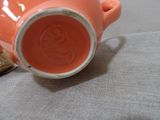 a small orange cup sitting on a table next to a book