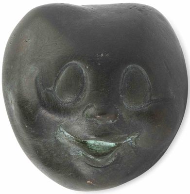 une sculpture noire représentant un visage souriant sur fond blanc