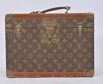 une vieille valise Louis Vuitton posée sur une surface blanche