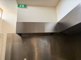 un panneau vert « Sortie de secours » au-dessus d'une cuisinière en acier inoxydable