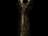 an ancient bronze figurine of a woman ' s head on a black background