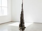 une sculpture représentant une tour, composée de tiges métalliques, dans une pièce