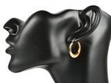 un gros plan sur la tête d'un mannequin portant une paire de boucles d'oreilles créoles en or
