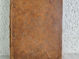 an old book sitting on top of a table next to a white wall
