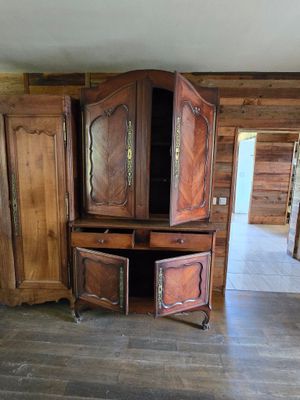une armoire en bois à deux portes, ouverte, au milieu d'une pièce