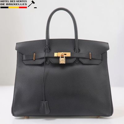 un sac à main en cuir noir muni d'un fermoir doré sur la poignée
