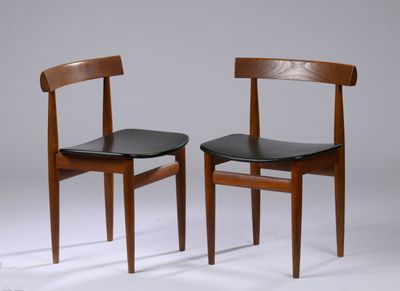 two wooden chairs with black leather seats against a gray background