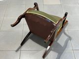 une chaise marron avec une assise verte, posée sur un sol carrelé