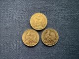 three gold coins sitting next to each other on a blue surface