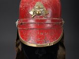 an old red and gold helmet on a black mannequin head
