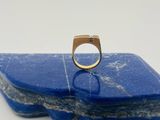 un gros plan d'une bague en or posée sur une pierre bleue