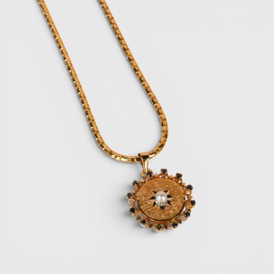 un collier en or avec un pendentif en forme de tournesol au bout d'une chaîne