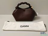 un sac marron posé sur une table, à côté d'un sac blanc