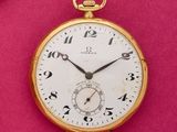 une montre de poche en or posée sur une surface rose