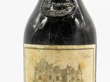 an old bottle of wine sitting on top of a white surface