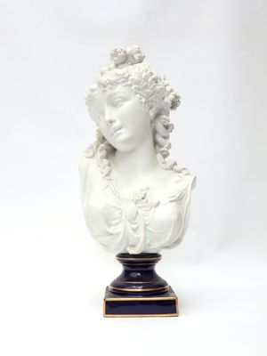 white bust of a woman with curly hair on a black and gold base