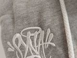 a close up of a grey hoodie with a white logo on it