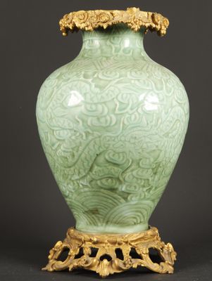 a green vase sitting on top of a table next to a black background