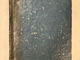 un vieux livre posé sur une table, à côté d'une feuille blanche