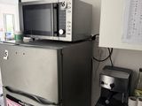 un réfrigérateur surmonté d'un micro-ondes, à côté d'une cafetière