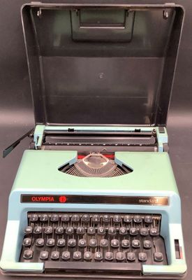 une vieille machine à écrire bleue posée sur une table noire