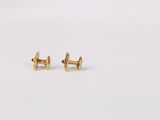 a pair of gold stud earrings on a white surface
