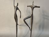 paire de sculptures métalliques représentant un homme et une femme, posées sur un socle