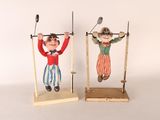 une paire de figurines vintage représentant des clowns, posées sur des socles en bois, sur fond blanc