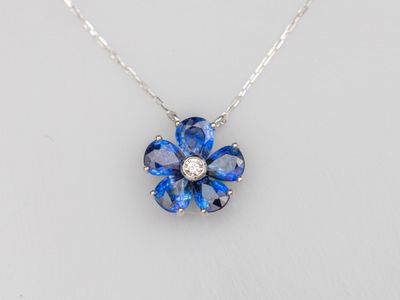 une photo d'un collier représentant une fleur bleue, orné d'un diamant au centre
