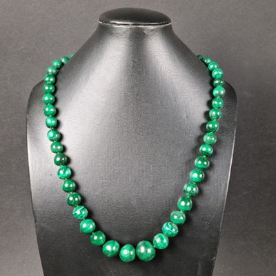 un collier de perles vertes sur un mannequin d'étalage
