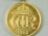 gold medal with a red ribbon around it and a crown on top of it