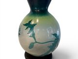 a vase that has a bird on it on a stand