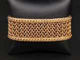 un gros plan d'un bracelet à maillons dorés posé sur un coussin noir