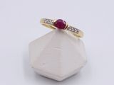 a close up of a gold ring with a ruby stone and diamonds